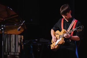 Młodzi muzycy szkoły IN ALTUM grający na instrumentach podczas świątecznego koncertu w MDK Witosa.